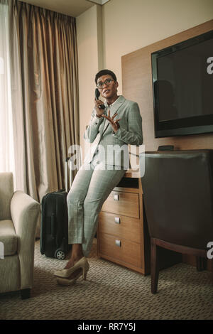Femme africaine sur business tour faire appel à partir de la chambre d'hôtel. Femme chef de conversations au téléphone fixe. Banque D'Images