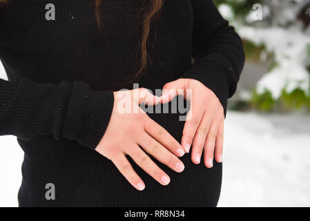 Détail de méconnaissable pregnant woman's belly en hiver Banque D'Images