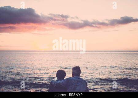 Couple de personnes âgées assis et s'étreindre l'autre face à la mer au coucher du soleil relaxant. Concept de vacances, loisirs, détente. Amour pour caucasian Banque D'Images