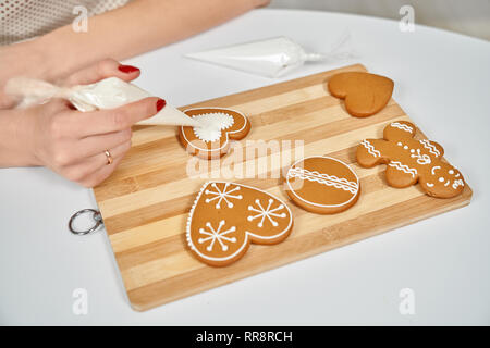 Friandises de Noël. Les mains d'épices brun décoration ornement blanc à l'aide de poche à douille. De délicieux biscuits de Noël de différentes formes de sucre Banque D'Images