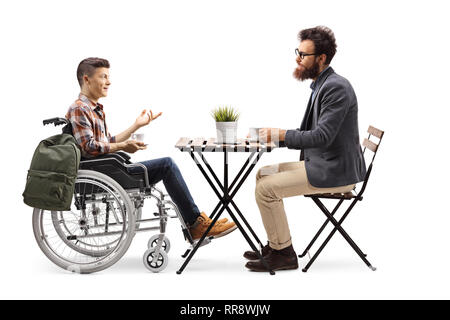 De toute la longueur un étudiant avec une tasse de café dans un fauteuil roulant assis dans un café et de parler à un homme barbu isolated on white Banque D'Images