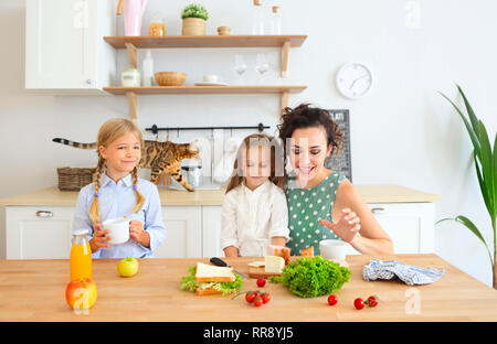 Happy young brunette mère avec mignon enfants le petit-déjeuner à l'accueil Banque D'Images