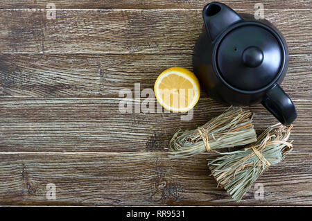 Matière sèche organique de la citronnelle (Cymbopogon flexuosus) en grappes et de citron sur une table en bois. Herbes pour le thé. Vue d'en haut. Banque D'Images