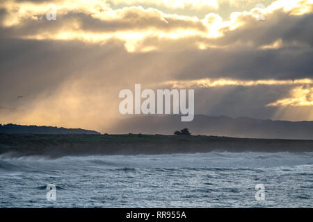 Lever tôt le matin avec les rayons de lumière en streaming à partir d'une ouverture dans les nuages, illuminant le littoral près de Cambria, San Simeon, en Californie. Banque D'Images