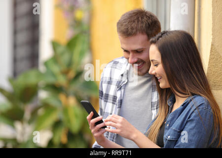 Happy couple using smart phone debout dans une rue colorée Banque D'Images