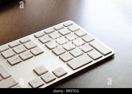 Un clavier numérique gris clair sur un bureau en bois sombre tableau Banque D'Images