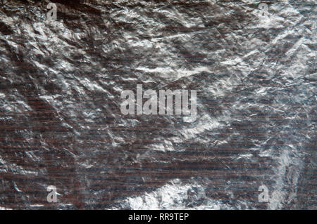 Cellophane transparent froissé sale sur une table en bois sombre. La texture peut être utilisé comme arrière-plan Banque D'Images