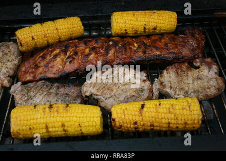 Plusieurs morceaux de la viande grillée et des épis de maïs sur un grill Banque D'Images