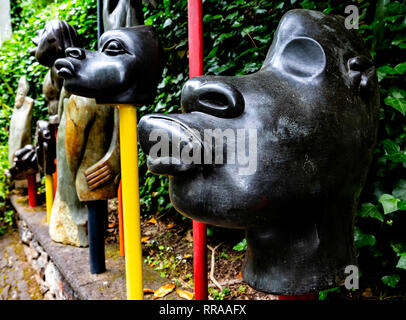 Têtes de pierre sculpté africain stylisé affiché sur poteaux, Jardins tropicaux de Monte Palace, Funchal, Madère, Portugal. Banque D'Images