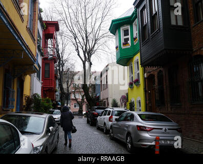 Istanbul, Turquie - 24 Février 2019 : traditionnel vieux maisons turques dans une rue de quartier Kuzguncuk avec une femme marche et des voitures en stationnement. Banque D'Images