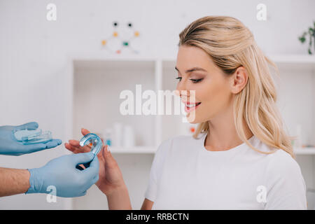 Belle femme prendre trainer appareil dentaire de l'orthodontiste au cours de rendez-vous dans une clinique Banque D'Images