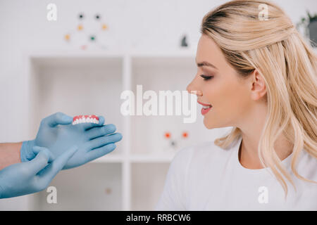 Belle femme à la recherche de gants en latex dentiste dents holding couvrir en clinique Banque D'Images