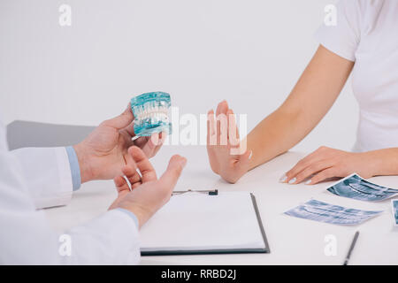 Portrait de femme faisant des gestes avec la main lors de nomination et refusant offre de mâchoire orthodontiste holding model isolated on white Banque D'Images