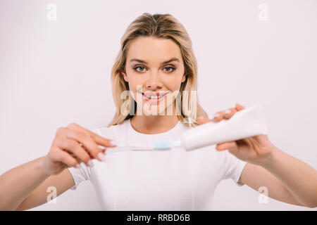 Beautiful smiling woman putting dentifrice sur une brosse à dents isolated on white Banque D'Images