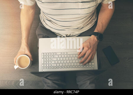 Homme assis sur le sol et en utilisant un ordinateur portable à la maison. Vue de dessus Banque D'Images
