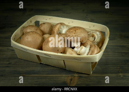 Crimini frais entier (Baby Bella) champignons dans le panier en bois sombre sur fond de table rustique Banque D'Images