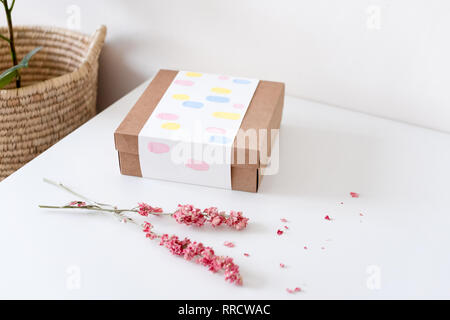 Du papier craft marron boîte-cadeau avec des fleurs séchées sur le tableau blanc. Focus sélectif. Banque D'Images