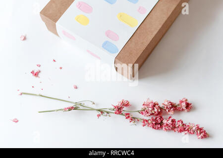 Du papier craft marron boîte-cadeau avec des fleurs séchées sur le tableau blanc. Focus sélectif. Banque D'Images