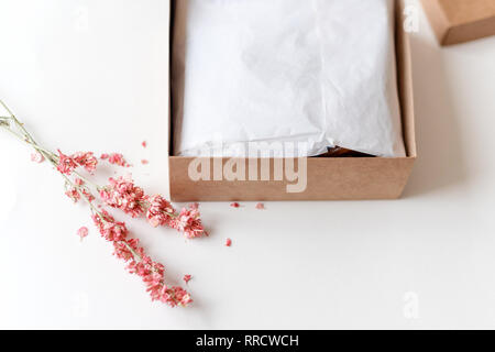 Du papier craft marron boîte-cadeau avec des fleurs séchées sur le tableau blanc. Focus sélectif. Banque D'Images
