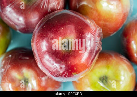 Concept d'utilisation de plastique excessive : pommes fraîches dans la cuisine d'enrubannage. Plus injustifié des produits alimentaires préemballés : fruits frais dans l'emballage plastique, close-up view Banque D'Images