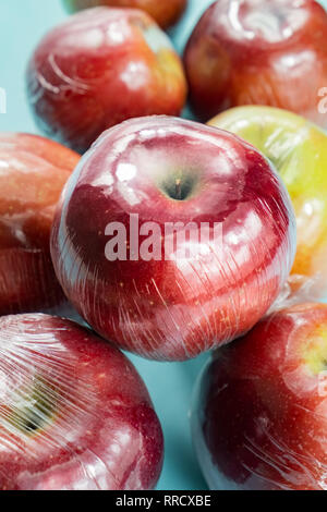 Concept d'utilisation de plastique excessive : pommes fraîches dans la cuisine d'enrubannage. Plus injustifié des produits alimentaires préemballés : fruits frais dans l'emballage plastique, close-up view Banque D'Images