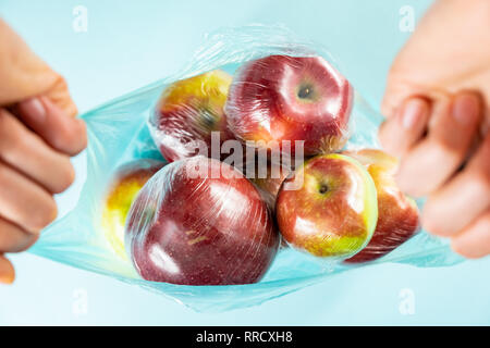 Concept d'utilisation de plastique excessive : pommes fraîches dans la cuisine l'envelopper dans un sac en plastique. Plus injustifié des produits alimentaires préemballés, vue d'en haut Banque D'Images