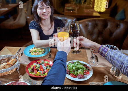 Groupe d'amis célébrer avec un toast et élever verres en fête. Beaux jeunes gens s'amuser dans l''élégant estaurant. Banque D'Images