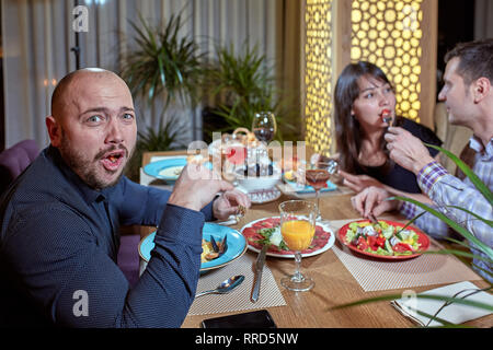 Le troisième est superflue. couple dans l'amour est en train de dîner dans un restaurant avec un seul ami Banque D'Images