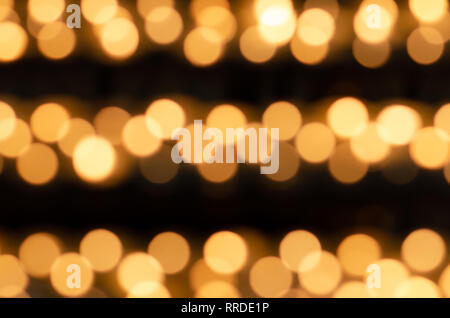 Beaucoup de belles bougies allumées dans une rangée avec une éclatante lumière jaune doré - out of focus Banque D'Images