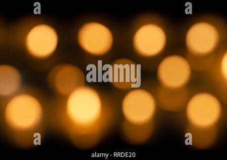 Beaucoup de belles bougies allumées dans une rangée avec une éclatante lumière jaune doré - out of focus Banque D'Images