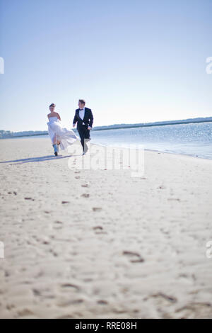 Mariée et le marié le long de la plage Banque D'Images