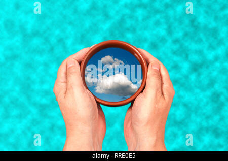Dans les mains d'une tasse avec la réflexion des nuages sur le fond de l'eau dans la piscine Banque D'Images