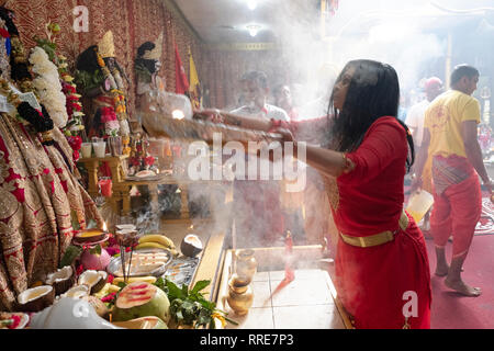 Un hindou pieux adorateur effectue le rituel de l'aarti, passant les flammes en face de statues de divinités. Dans le Queens, New York. Banque D'Images