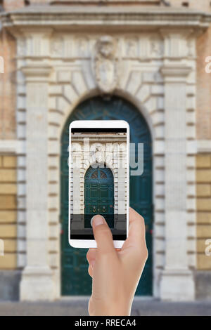 Un homme fait une photo de l'ancien porte verte avec arc de Palazzo Cesi 16e siècle. Rome, Italie sur un téléphone mobile Banque D'Images