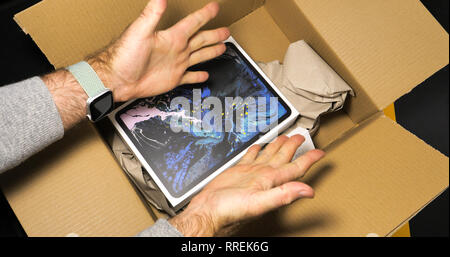 PARIS, FRANCE - NOV 16, 2018 : Happy man unboxing dernière iPad Smart tablette Apple et 2 crayons fabriqués par Apple Ordinateurs dans un environnement de bureau moderne table jaune Banque D'Images