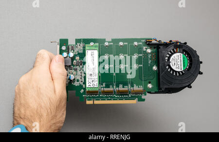 Paris, France - Oct 14, 201 : Homme il guy holding contre l'arrière-plan gris un puissant lecteur Dell ouvert Ultra-Speed NVMe Quad M.2 PCIe x16 avec un SK Hynix carte avec ventilateur Sunon Banque D'Images