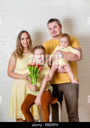 Funny portrait de famille sur Pâques de la mère, le père et les enfants portant des vêtements jaune et posant contre mur blanc Banque D'Images