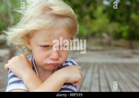 Face portrait de contrarié et mécontent caucasian kid avec bras croisés. Concept de l'enfant en colère et pour les relations familiales, les questions des problèmes sociaux Banque D'Images