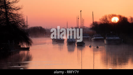 Wareham, Dorset, UK. 26 février 2019. Météo France : Le ciel s'allume avec des teintes orange et rose comme la brume se lève au-dessus de la rivière Frome sur un froid matin de février. Une scène paisible que la voile bateaux amarrés le long de la rivière se reflètent dans l'eau calme sur le début de ce qui est défini pour être une autre journée ensoleillée glorieusement. Credit : Celia McMahon/Alamy Live News Banque D'Images