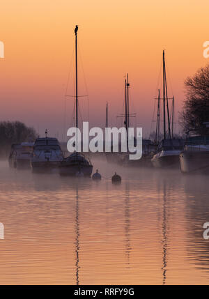 Wareham, Dorset, UK. 26 février 2019. Météo France : Le ciel s'allume avec des teintes orange et rose comme la brume se lève au-dessus de la rivière Frome sur un froid matin de février. Une scène paisible que la voile bateaux amarrés le long de la rivière se reflètent dans l'eau calme sur le début de ce qui est défini pour être une autre journée ensoleillée glorieusement. Credit : Celia McMahon/Alamy Live News Banque D'Images