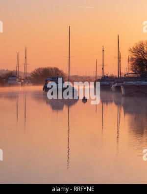 Wareham, Dorset, UK. 26 février 2019. Météo France : Le ciel s'allume avec des teintes orange et rose comme la brume se lève au-dessus de la rivière Frome sur un froid matin de février. Une scène paisible que la voile bateaux amarrés le long de la rivière se reflètent dans l'eau calme sur le début de ce qui est défini pour être une autre journée ensoleillée glorieusement. Credit : Celia McMahon/Alamy Live News Banque D'Images