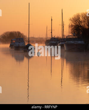 Wareham, Dorset, UK. 26 février 2019. Météo France : Le ciel s'allume avec des teintes orange et rose comme la brume se lève au-dessus de la rivière Frome sur un froid matin de février. Une scène paisible que la voile bateaux amarrés le long de la rivière se reflètent dans l'eau calme sur le début de ce qui est défini pour être une autre journée ensoleillée glorieusement. Credit : Celia McMahon/Alamy Live News Banque D'Images