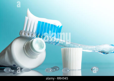 Nouvelle brosse à dents avec du dentifrice close-up dans la salle de bains sur un miroir table avec gouttes d'eau sur un fond bleu dans la lumière du soleil Banque D'Images