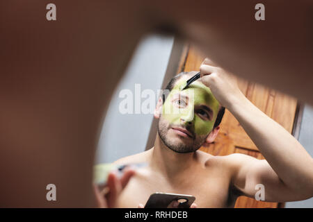 L'homme d'appliquer un masque de beauté pour les hommes dans la salle d'accueil Banque D'Images