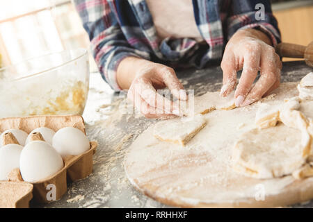 Jeune femme au foyer à la maison debout dans la cuisine coupe pâte de forme close-up Banque D'Images