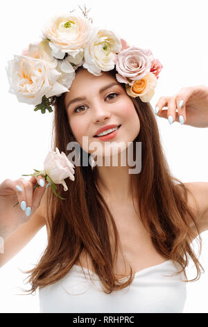 Belle jeune fille souriant et posant avec des fleurs sur fond blanc. Banque D'Images