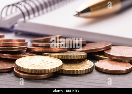 Pile de pièces en euro de l'euro sur la vieille table en bois noir. Stylo, ordinateur portable. Concept de planification des dépenses d'accueil et de payer les factures, la comptabilité Banque D'Images