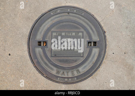 Couvercle de trou d'fer dans une rue de la ville de Bryan, Texas, USA ; l'évacuation de l'eau et d'égout ; fait par East Jordan Iron Works. Banque D'Images