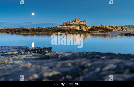 Château de Bamburgh lune reflétée dans l'eau toujours au crépuscule, Bamburgh, Northumberland, Angleterre, Royaume-Uni, Europe Banque D'Images