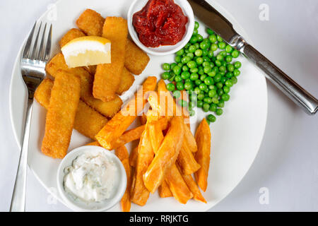 Repas dans un pub anglais classique de Fish fingers, chips et petits pois servi avec du ketchup, sauce tartare et frais de citron. Banque D'Images